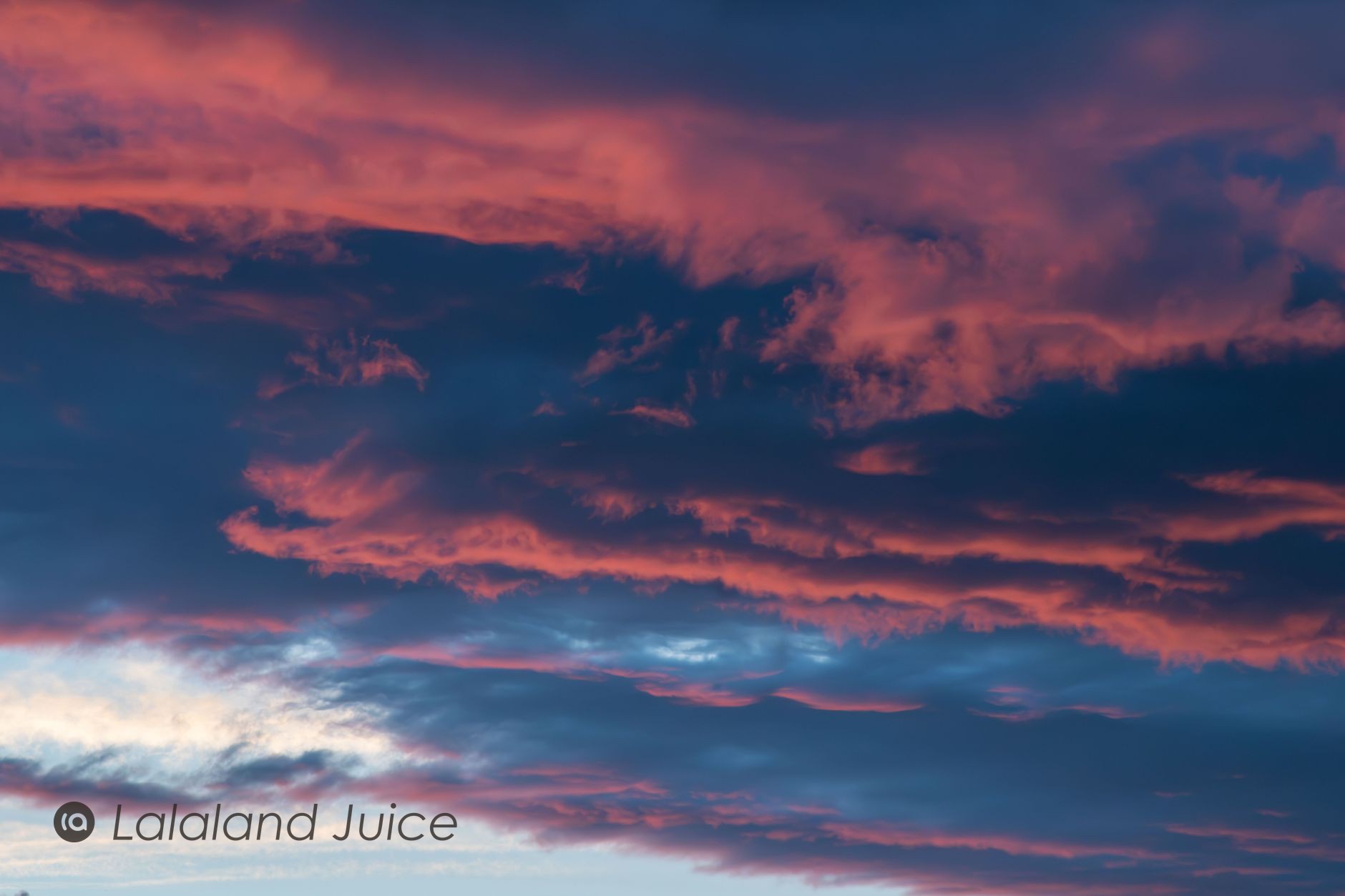A soft pink-and-blue twilight sky, the day's last light going down — the Lalaland Juice mark set within.